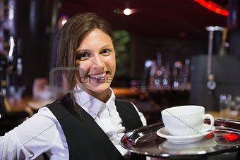 Happy barmaid holding tray with coffee
