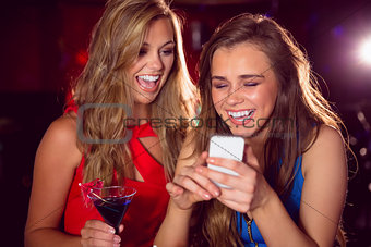 Pretty friends looking at smartphone together