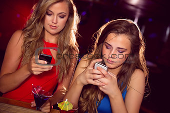 Pretty friends looking at smartphones