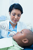 Female dentist examining boys teeth in dentists chair