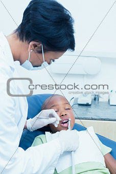 Female dentist examining boys teeth in dentists chair