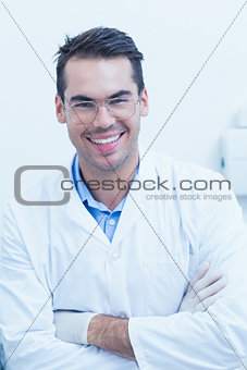 Happy male dentist with arms crossed