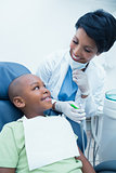 Smiling female dentist examining boys teeth