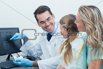 Dentist with assistant showing little girl her mouth x-ray