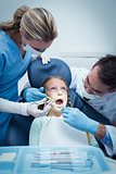 Dentist with assistant examining girls teeth
