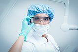 Female dentist wearing surgical mask and safety glasses