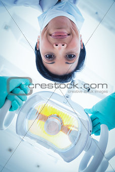 Low angle of female dentist adjusting light