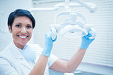 Smiling female dentist adjusting light