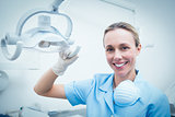 Portrait of female dentist adjusting light