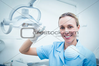 Portrait of female dentist adjusting light