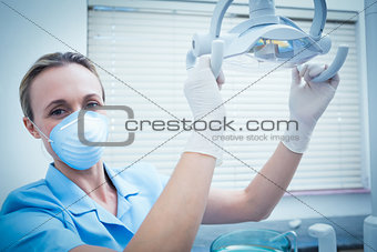 Portrait of dentist adjusting light