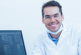 Smiling male dentist with computer monitor
