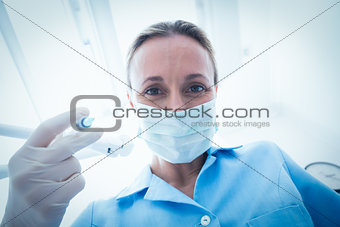 Female dentist in surgical mask holding injection