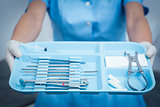 Mid section of dentist holding tray of tools