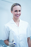 Smiling female dentist holding clipboard