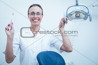 Smiling female dentist holding toothbrush