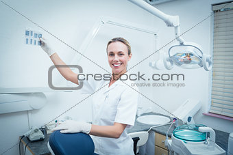 Smiling female dentist looking at x-ray