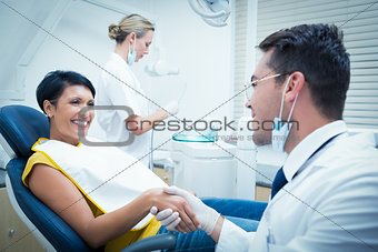 Male dentist shaking hands with woman