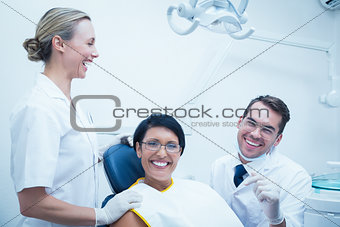 Cheerful dentist and assistant with female patient