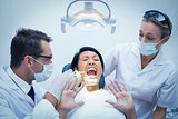 Male dentist with assistant examining womans teeth