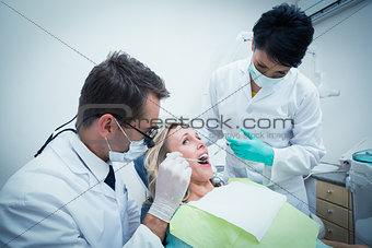 Male dentist with assistant examining womans teeth