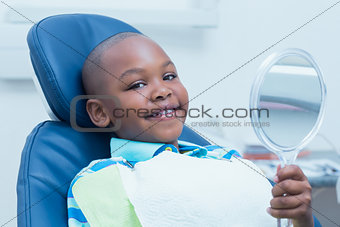 Boy holding at mirror in the dentists chair