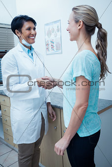 Female dentist shaking hands with woman
