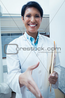 Smiling female dentist offering handshake