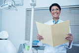 Smiling female dentist reading reports