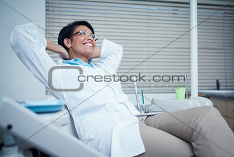 Relaxed smiling female dentist sitting on chair
