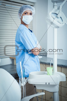 Dentist wearing surgical mask with arms crossed