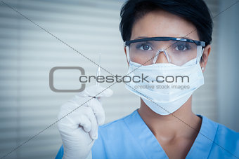 Dentist in surgical mask holding dental tool