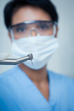 Dentist in surgical mask holding dental drill
