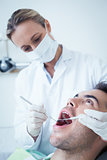 Female dentist examining mans teeth