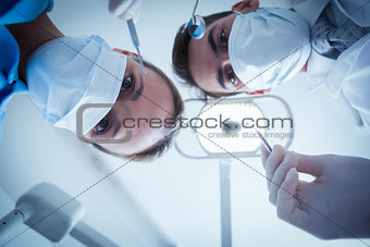 Dentists in surgical masks holding dental tools
