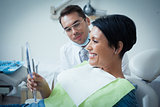 Side view of smiling female patient with dentist
