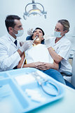 Dentist with assistant examining womans teeth