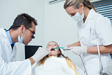 Dentist  with assistant examining girls teeth