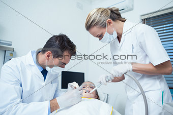 Male dentist with assistant examining girls teeth