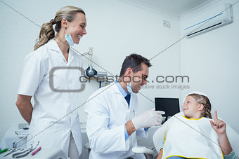Male dentist  and assistant talking to girl