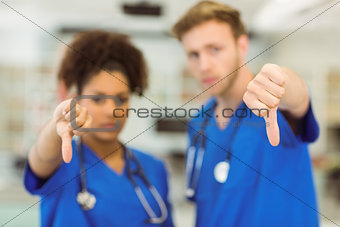 Young medical students showing thumbs down