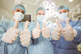 Team of surgeons looking at camera showing thumbs up