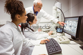 Science students looking at microscopic image on computer with lecturer