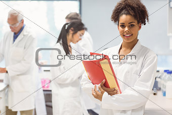 Science student holding large folder in lab