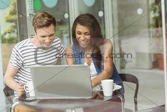 Smiling friends with chocolate cake using laptop