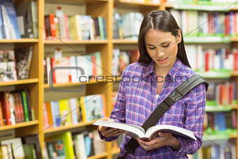 Smiling university student reading textbook