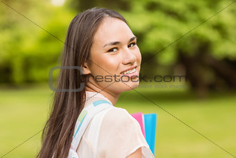 Portrait of a smiling student with a shoulder bag and holding book