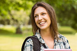Portrait of a smiling student with a shoulder bag and holding book