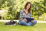 Smiling student sitting and using tablet pc