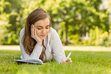 University student lying and writing on notepad